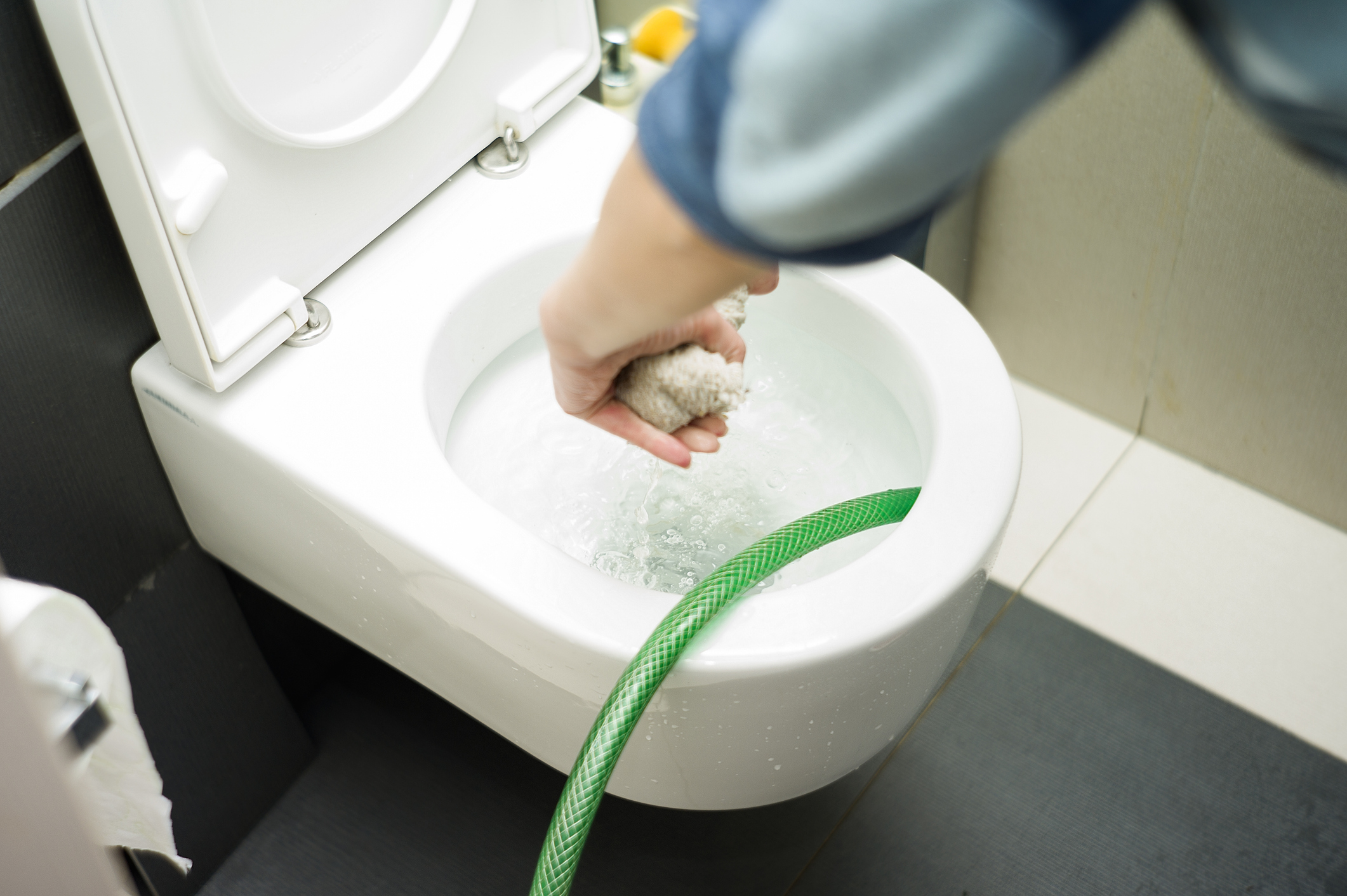 A bathroom toilet with the water level high in the bowl and not draining, indicating the toilet will not flush