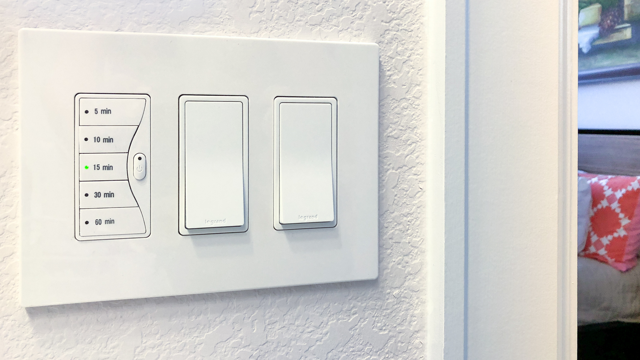 A bathroom wall switch being replaced with a digital timer switch, with the exhaust fan switch box open and wiring visible