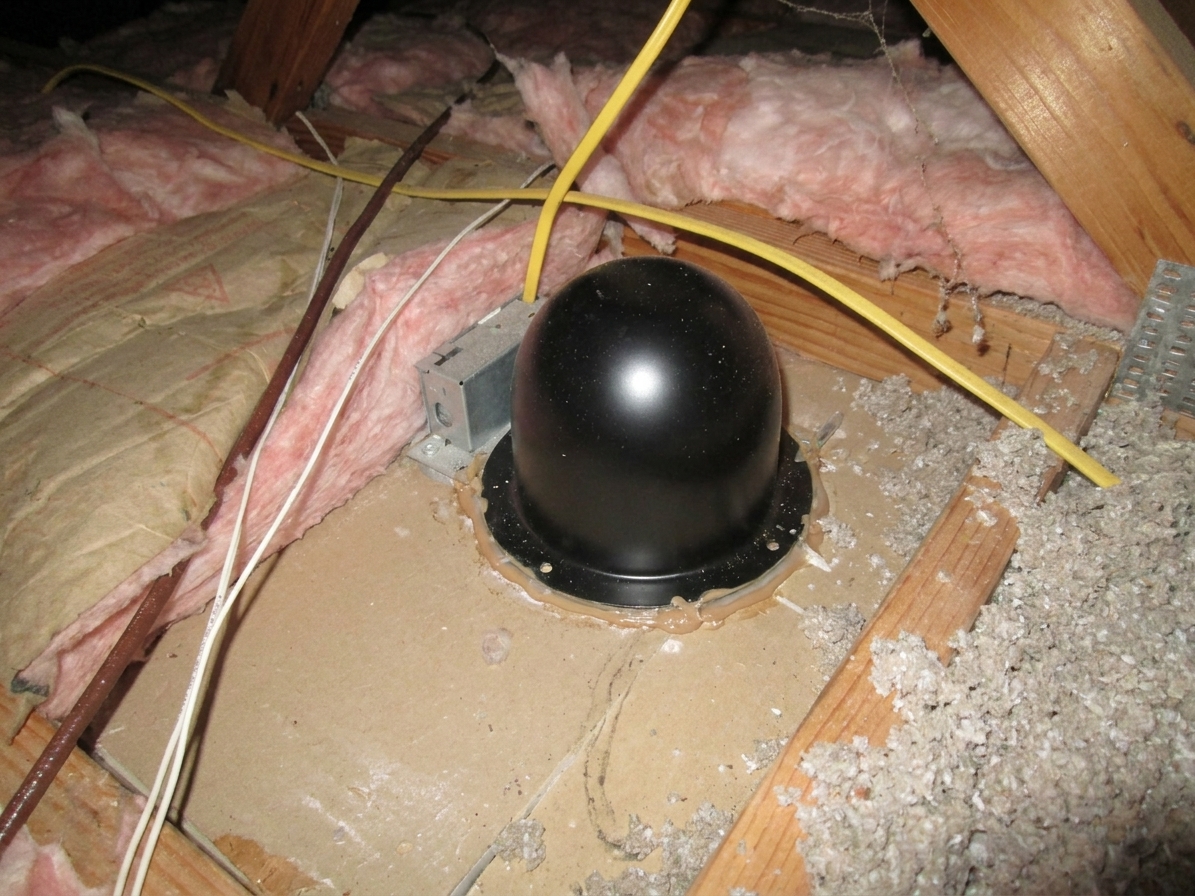 A listed recessed light cover installed over a can light in an attic with sealed edges, ready for loose-fill insulation to surround it