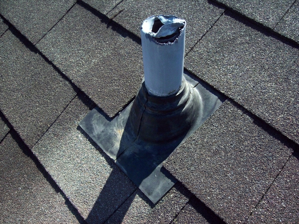 A plumbing vent stack protruding through an asphalt shingle roof with a rubber flashing boot around the pipe