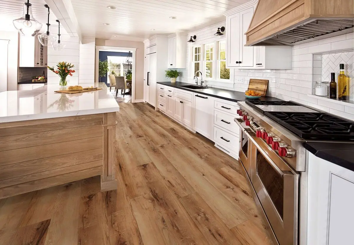 A real kitchen floor installed with vinyl planks in a warm oak color, showing tight seams and a natural wood-grain texture under daylight