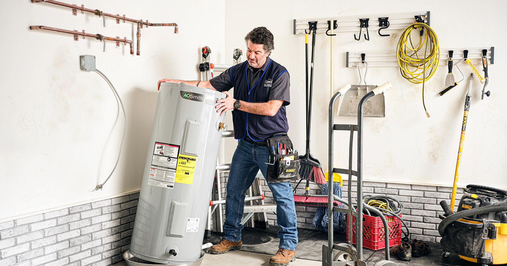 A standard residential tank water heater installed with visible hot and cold water lines and a shutoff valve