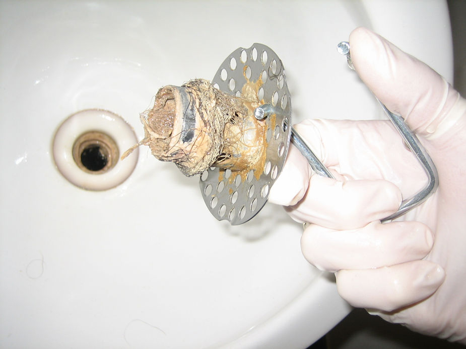 A white bathtub with several inches of standing water pooled around the drain, showing a typical slow-drain clog situation