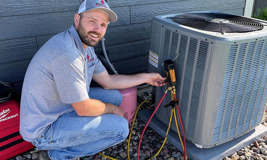 An outdoor central air conditioner condenser unit next to a house with the service panel visible and the surrounding area cleared of leaves