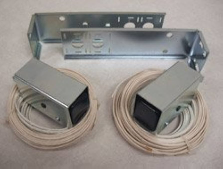 Close-up photo of two garage door photo-eye safety sensors mounted near the floor on each side of the opening, with one sensor indicator light visible