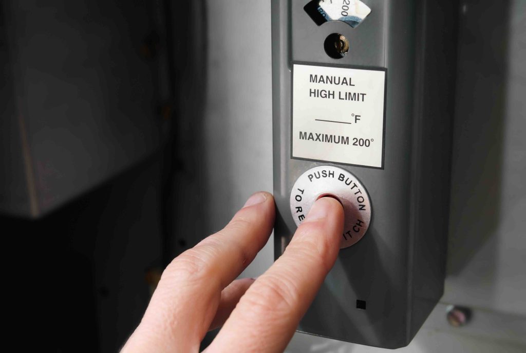 The red high-limit reset button on an electric water heater thermostat behind the access panel